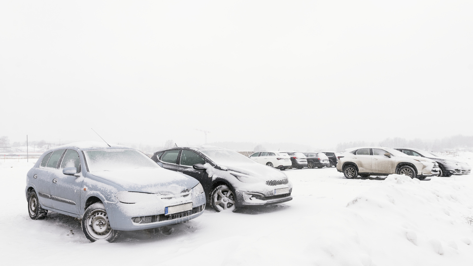 Parkerade bilar i snötäckt landskap.
