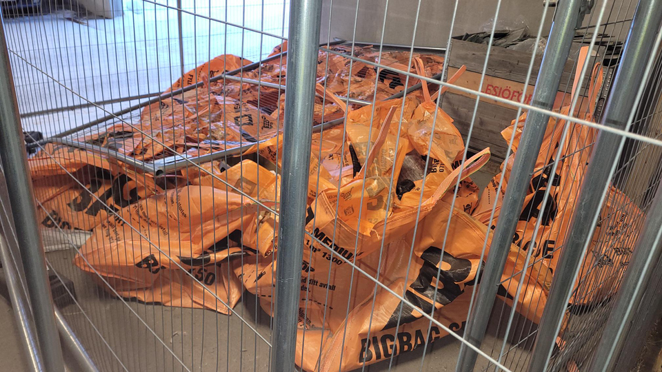 En hög med orangefärgade påsar i en bur.