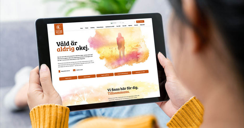 Kvinna håller i en surfplatta som visar Centrum mot vålds webbplats